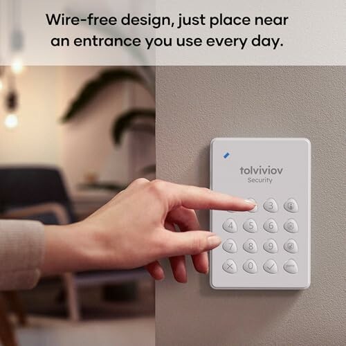 Person using wireless security keypad on wall.